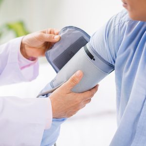 Close-up image of doctor applying blood pressure cuff to the arm of a female patient